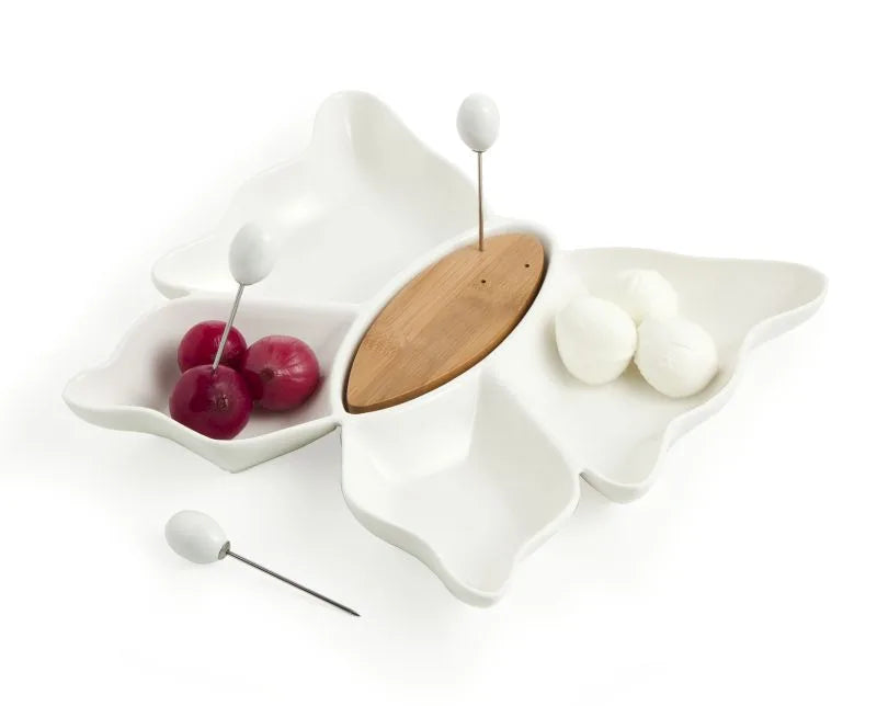 Entremesera de porcelana blanca con forma de mariposa sobre un soporte de bambú natural.