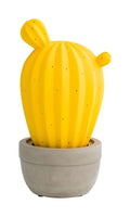Lámpara de sobremesa con forma de cactus, fabricada en porcelana amarilla, sobre un fondo neutro.