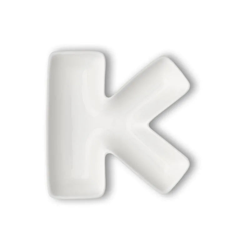 Letra decorativa "K" en porcelana blanca, vista frontal sobre fondo neutro.