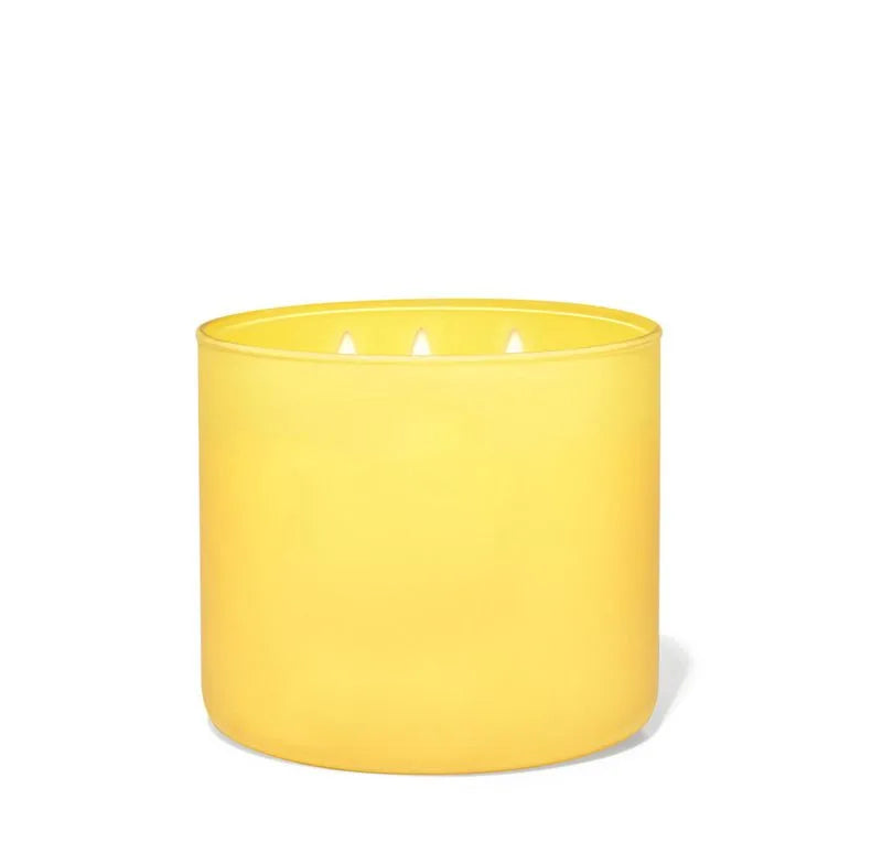 Vela perfumada de 3 mechas en recipiente de cristal amarillo, con cera de soja y aroma a limón.
